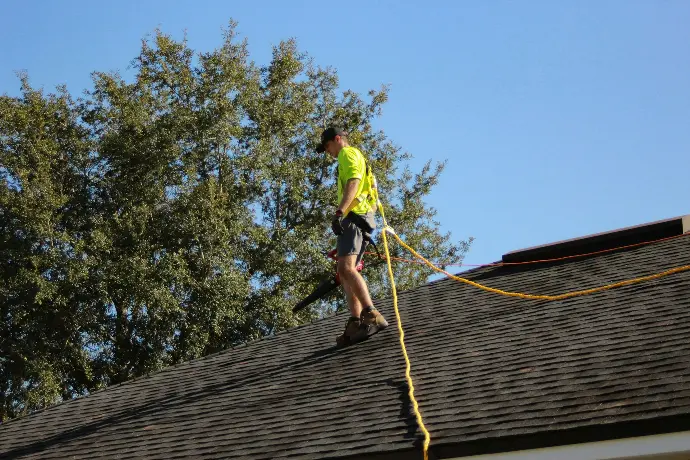 a man on a roofing contractor San Antonio TXworking with a rope